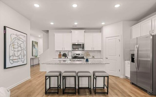 1260 Riverstone Road Jonesboro, GA 30236 - Photo 6 of 45 a kitchen with stainless steel appliances granite countertop a dining table chairs refrigerator and cabinets
