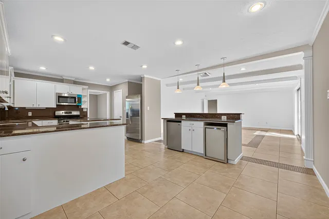 a kitchen with kitchen island granite countertop a refrigerator and a sink
