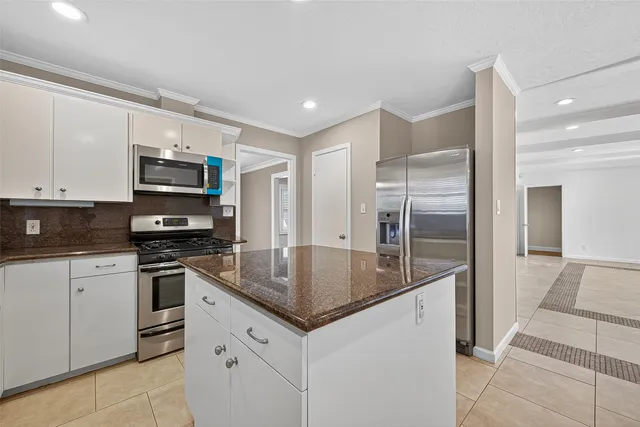 a kitchen with stainless steel appliances granite countertop a refrigerator a stove and a sink