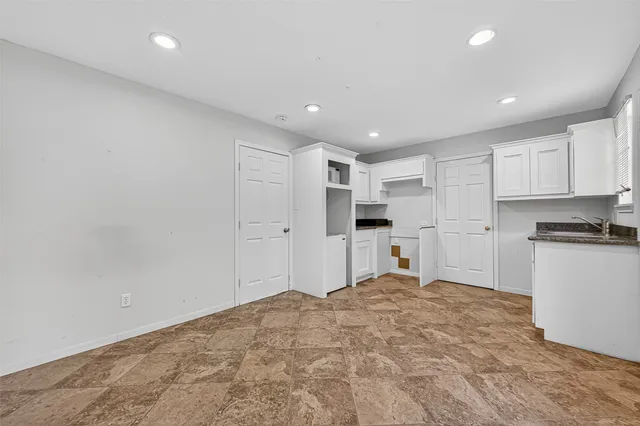 a large white kitchen with kitchen island a sink stainless steel appliances and white cabinets