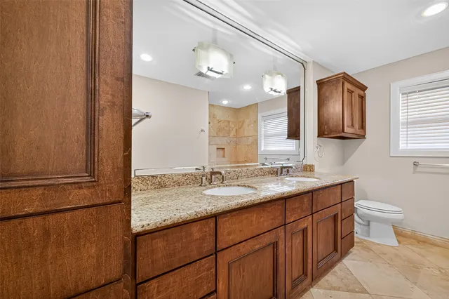a bathroom with a granite countertop sink a toilet and mirror