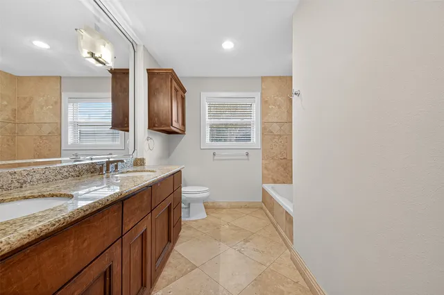 a bathroom with a granite countertop sink a large mirror and a toilet