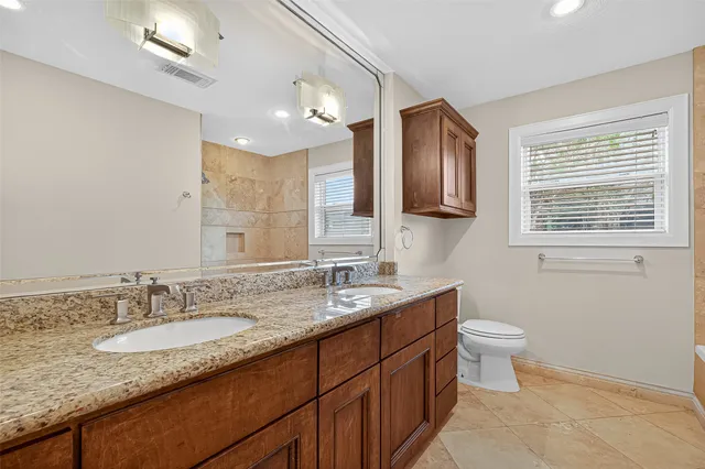 a bathroom with a granite countertop sink a toilet and a mirror