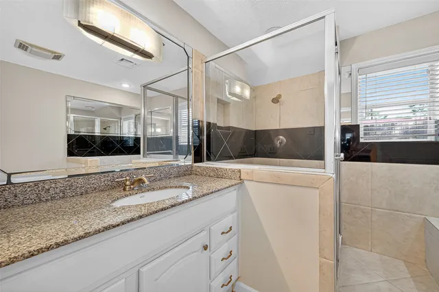 a bathroom with a granite countertop sink a mirror and shower