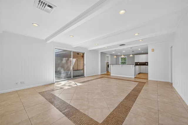 a view of an empty room with kitchen and window