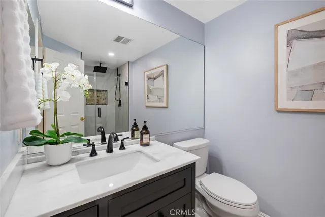 a bathroom with a sink a toilet a mirror and shower