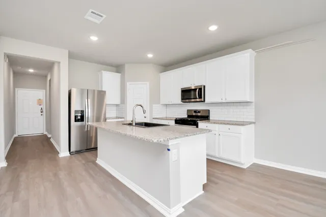 a view of kitchen with stainless steel appliances granite countertop a sink a stove a refrigerator and a window