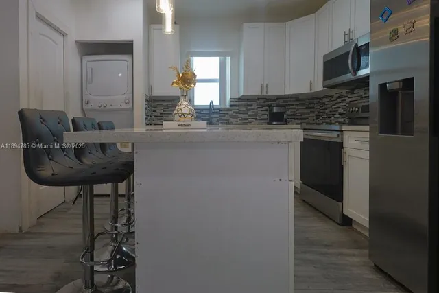 a kitchen with kitchen island granite countertop a sink cabinets and stainless steel appliances