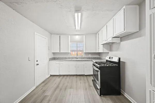 a kitchen with granite countertop a sink a stove and cabinets