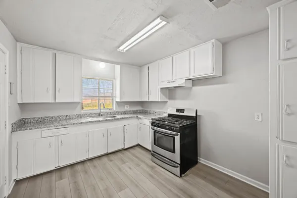 a kitchen with stainless steel appliances granite countertop a stove a sink and white cabinets