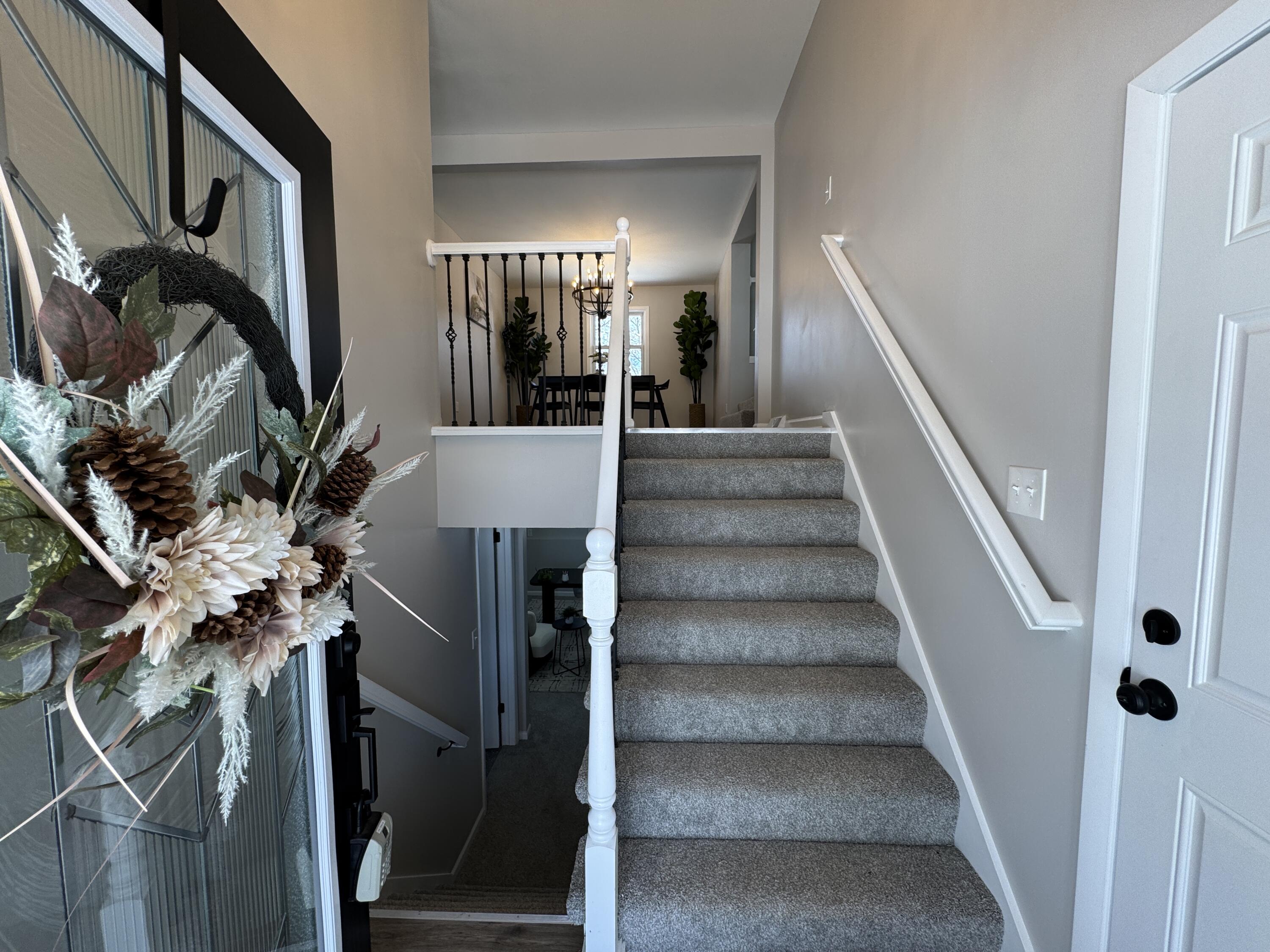 9383 Roosevelt Street Crown Point, IN 46307 - Photo 2 of 20 a view of staircase with lots of frames on wall and a chandelier