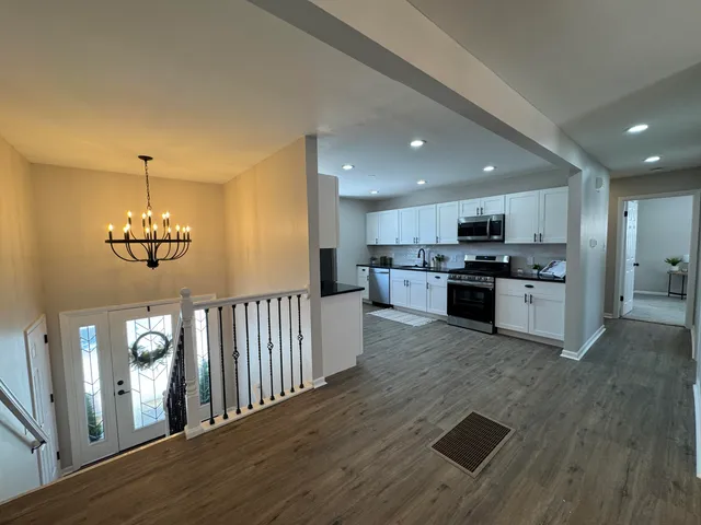 a kitchen with stainless steel appliances granite countertop a refrigerator a stove oven a sink dishwasher and white cabinets with wooden floor