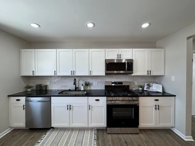 a kitchen with stainless steel appliances granite countertop a stove a sink and a microwave