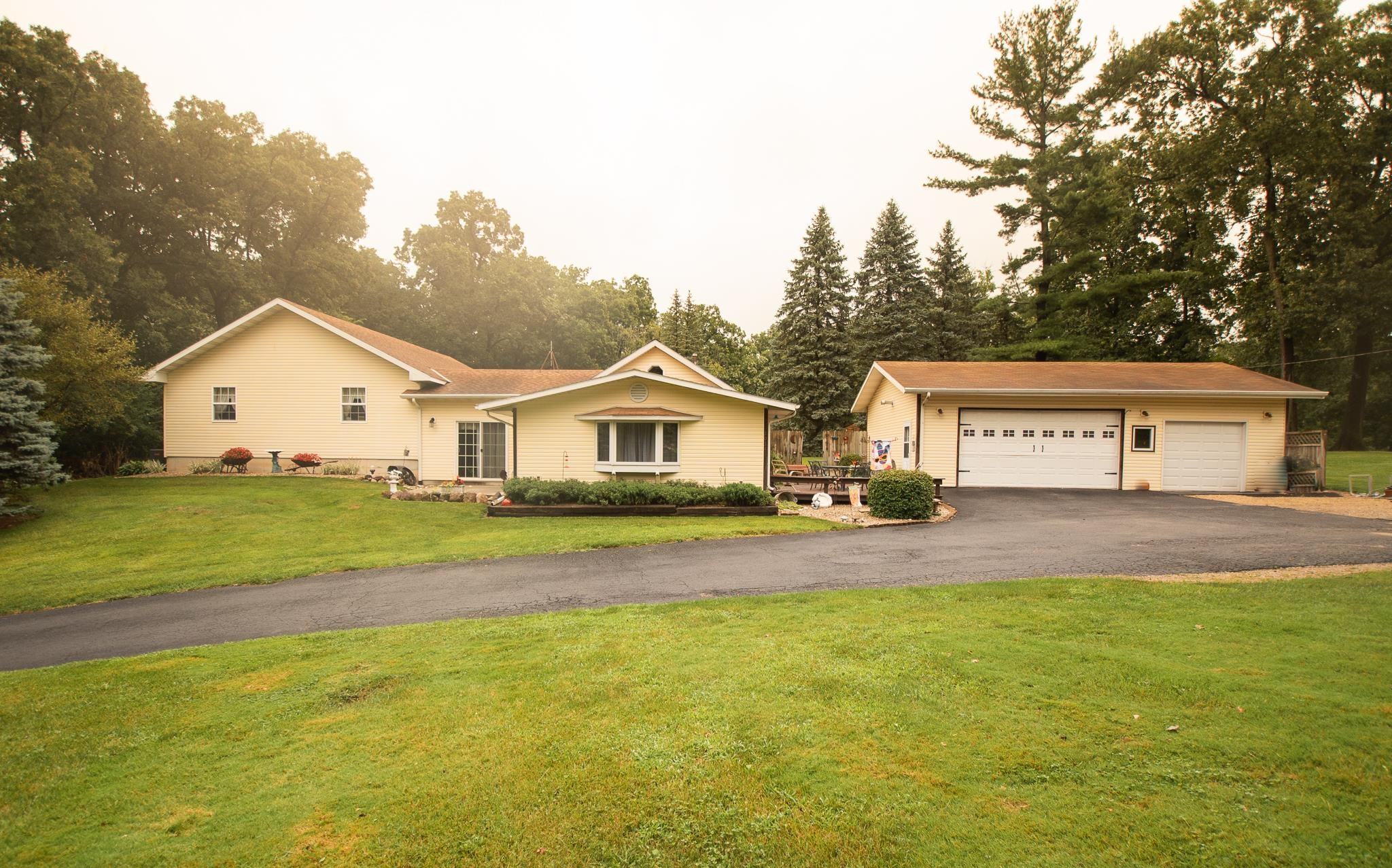 a view of white house with a big yard and large trees