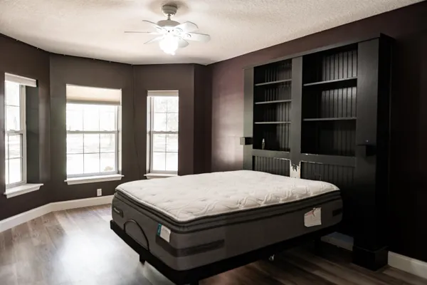 an empty room with wooden floor fan and windows