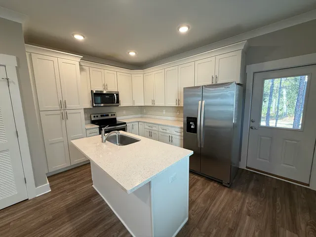 a kitchen with kitchen island white cabinets appliances and wooden floor
