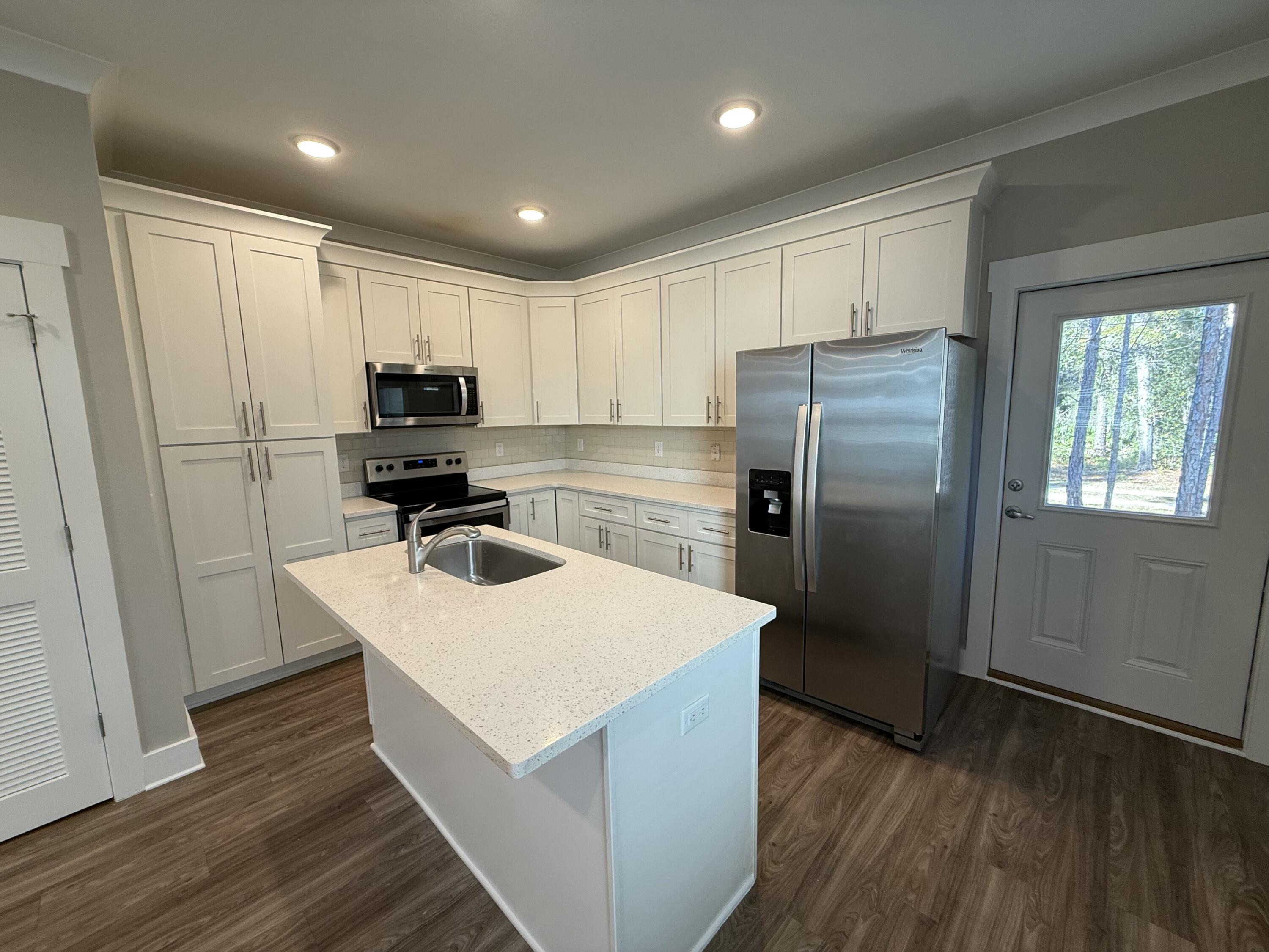 142 North Sand Palm Road Freeport, FL 32439 - Photo 12 of 26 a kitchen with kitchen island white cabinets appliances and wooden floor