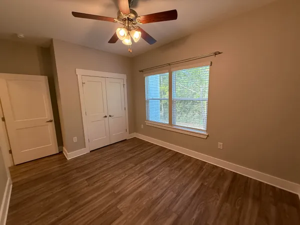 an empty room with wooden floor fan and windows