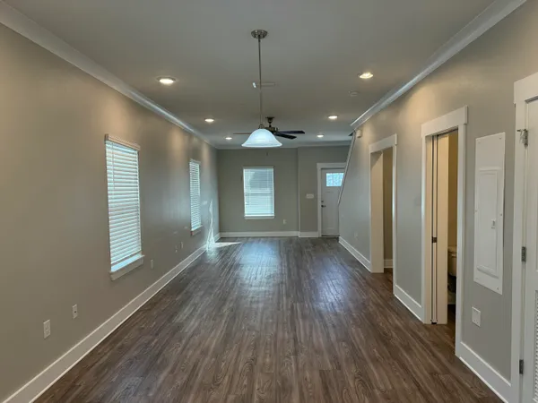 a view of an empty room with wooden floor and a window