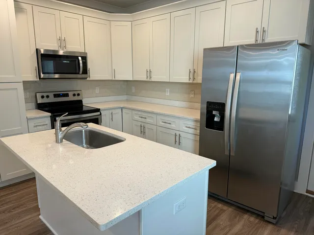 a kitchen with kitchen island a counter appliances a sink and cabinets