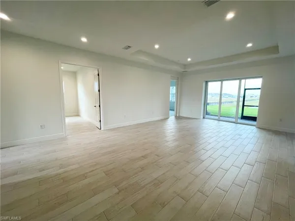 an empty room with wooden floor and natural light