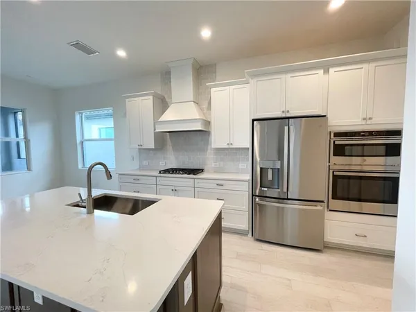 a kitchen with kitchen island granite countertop a sink and refrigerator