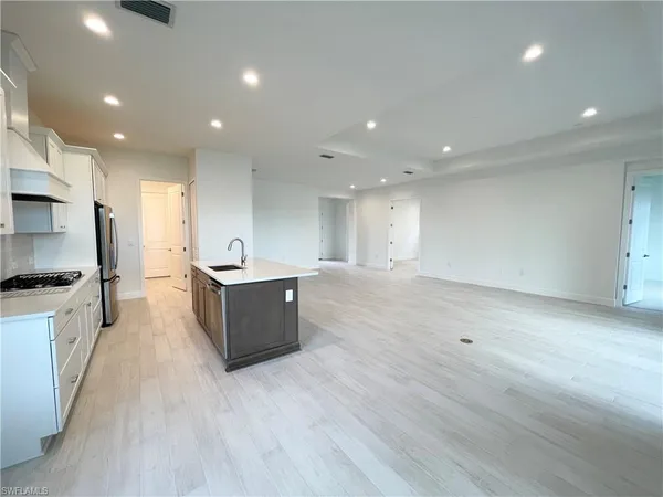 a large kitchen with stainless steel appliances a large counter top a stove and a wooden floors