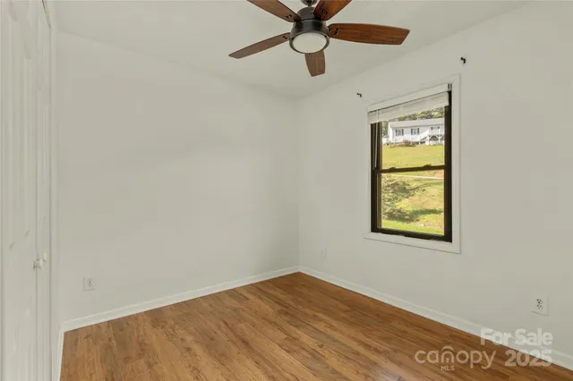an empty room with a window and a fan