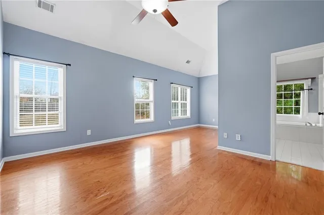 an empty room with wooden floor and windows