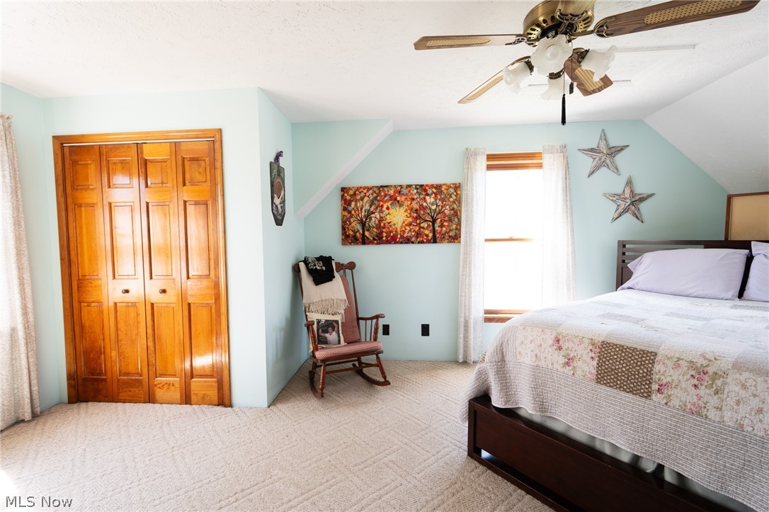 14027 Mayfield Road Huntsburg, OH 44046 - Photo 20 of 50 Carpeted room featuring a ceiling fan with integrated lighting, a window with natural wood trim, and bi-fold closet doors with wood paneling