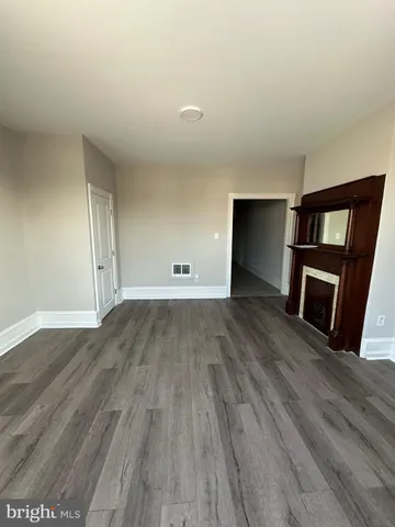 a view of empty room with wooden floor and fireplace