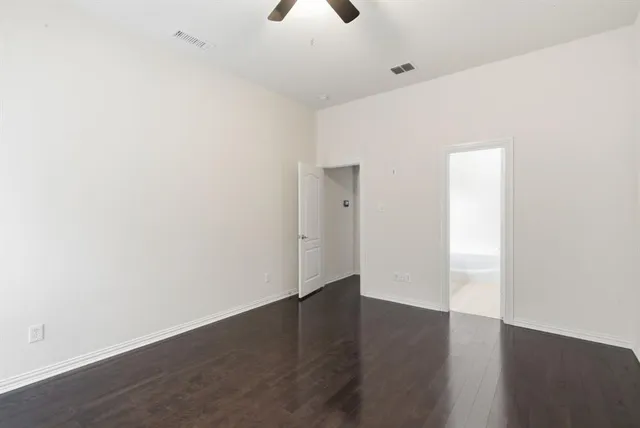an empty room with wooden floor cabinet and windows