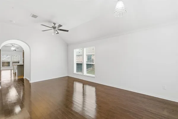 a view of empty room with wooden floor and fan