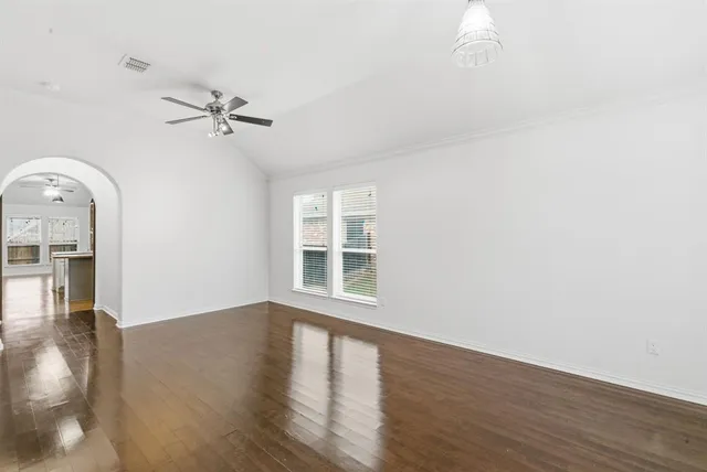 a view of empty room with wooden floor and fan