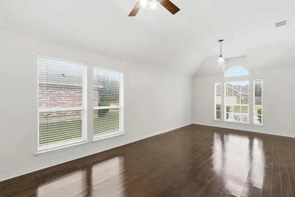 a view of an empty room with wooden floor and windows
