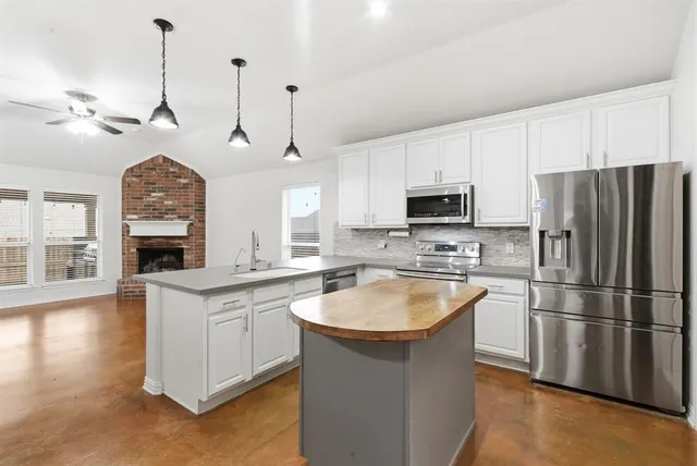 a kitchen with kitchen island a sink stainless steel appliances and wooden floor