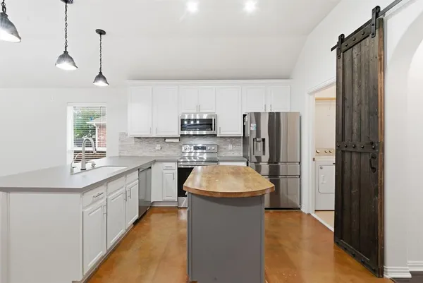 a kitchen with stainless steel appliances a sink stove refrigerator and cabinets