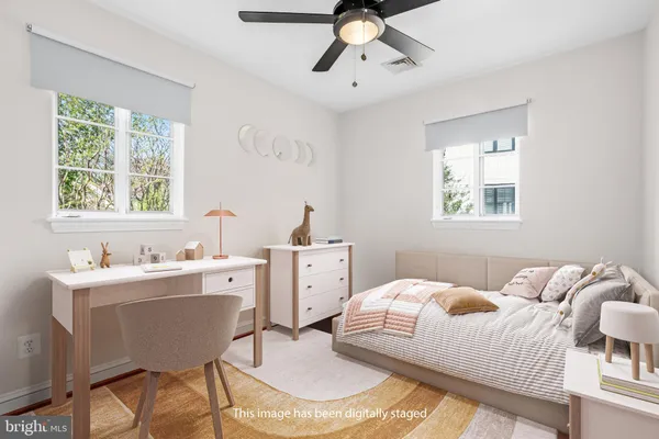 a bedroom with a white bed a desk and chair with window