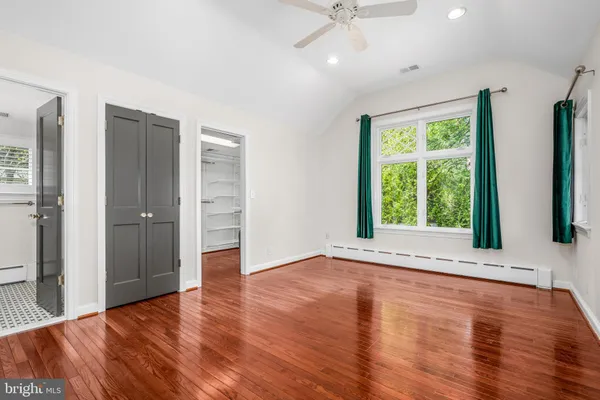 an empty room with wooden floor cabinet and windows
