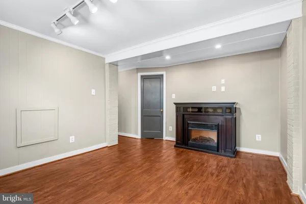 a view of an empty room with wooden floor and a fireplace