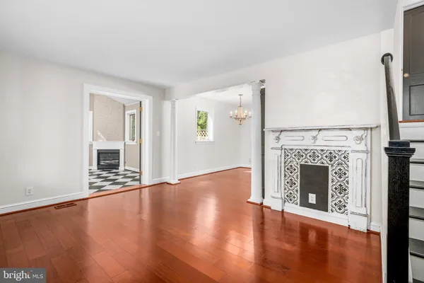 a view of an empty room with wooden floor fireplace and a window