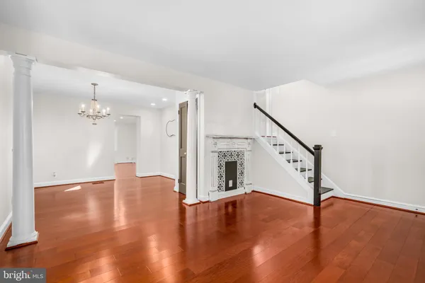 a view of an empty room with wooden floor and staircase