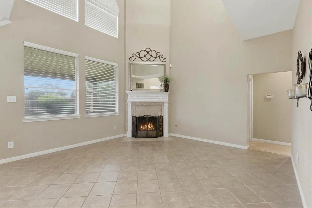 4838 Roaring Springs Road Pasadena, TX 77505 - Photo 14 of 38 Bright and spacious living area with high ceilings, featuring large windows, a cozy fireplace, and tile flooring.