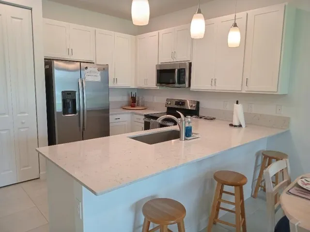 a kitchen with stainless steel appliances a sink a microwave a refrigerator and cabinets