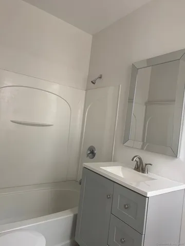 a bathroom with a bathtub shower sink vanity and toilet