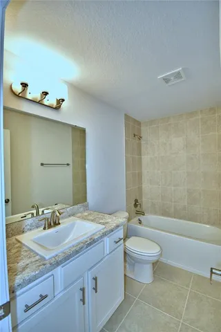 a spacious bathroom with a granite countertop toilet sink and mirror