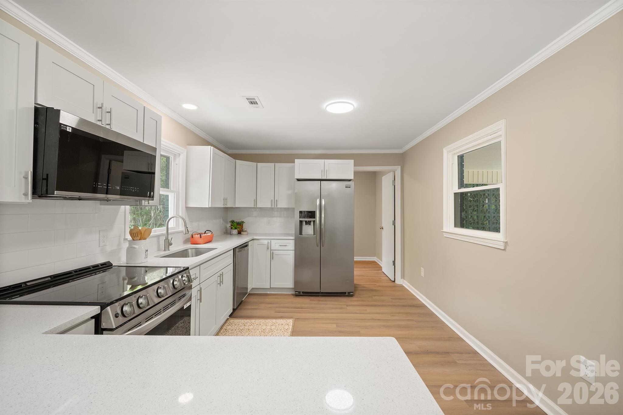 624 Flicker Street Concord, NC 28027 - Photo 17 of 47 a kitchen with stainless steel appliances granite countertop a refrigerator a stove top oven a sink dishwasher and white cabinets with wooden floor