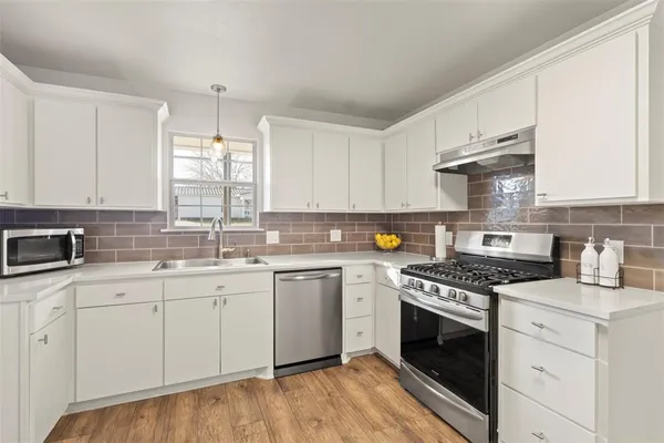 a kitchen with granite countertop a sink cabinets stainless steel appliances and a window
