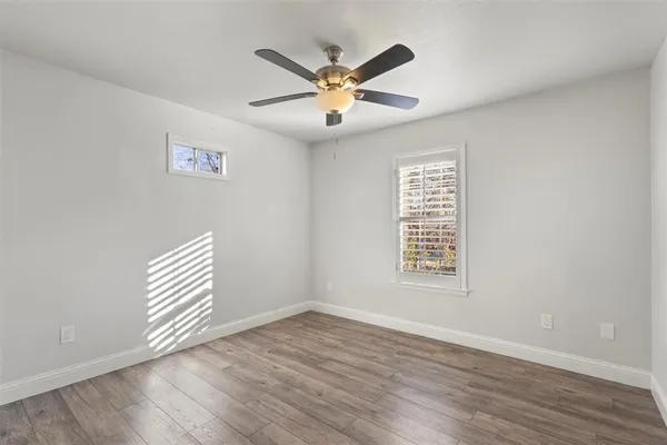 an view of an empty room with wooden floor and a ceiling fan