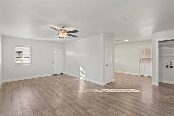 an empty room with wooden floor and a ceiling fan